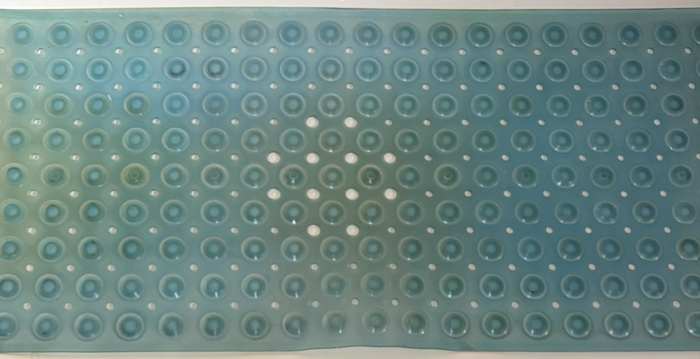 Old blue bath mat with many white holes and a cross of larger white holes. Three are highlighted in orange.